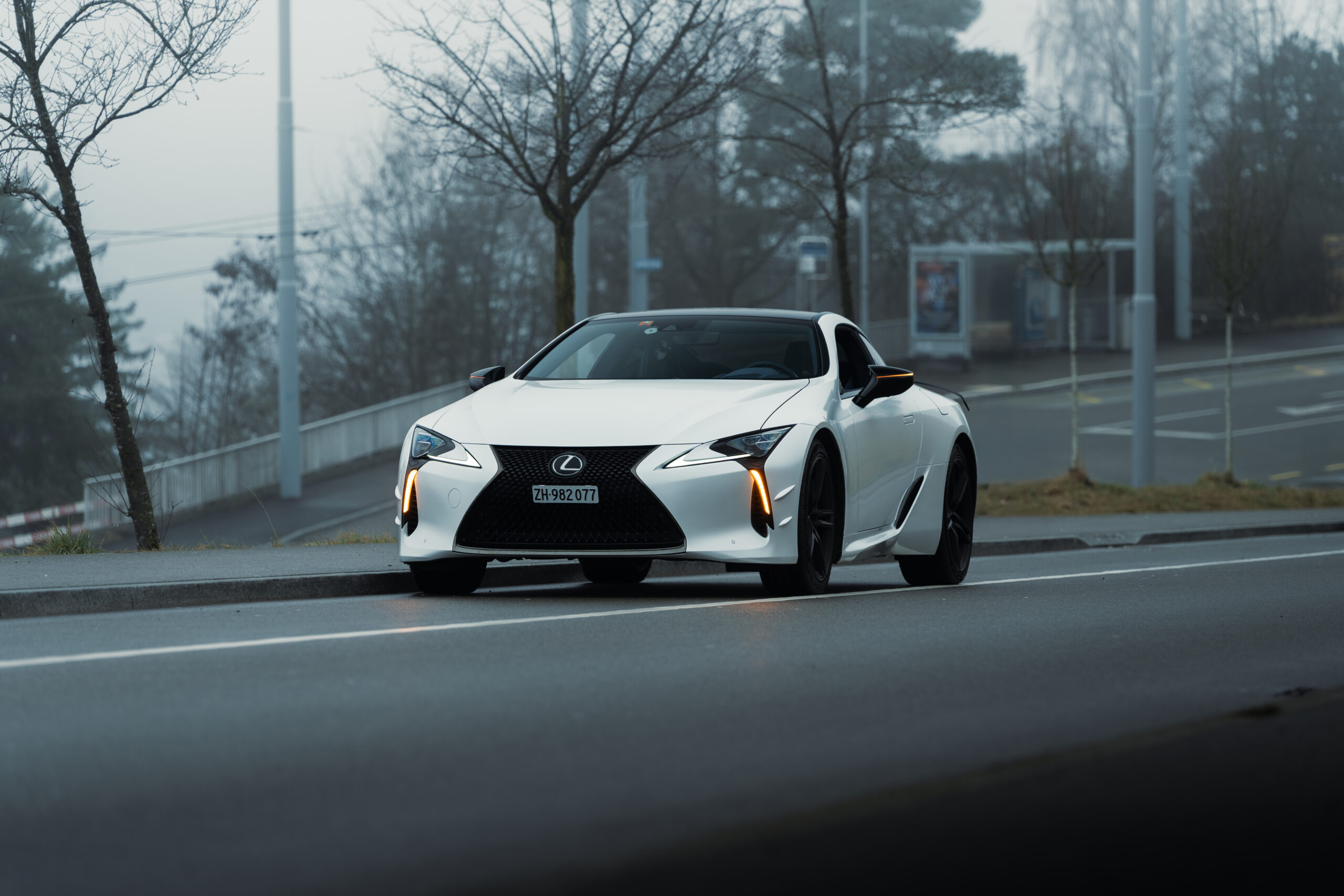 A Lexus LC500 Ultimate Edition parked by the road in foggy conditions with its hazard lights on