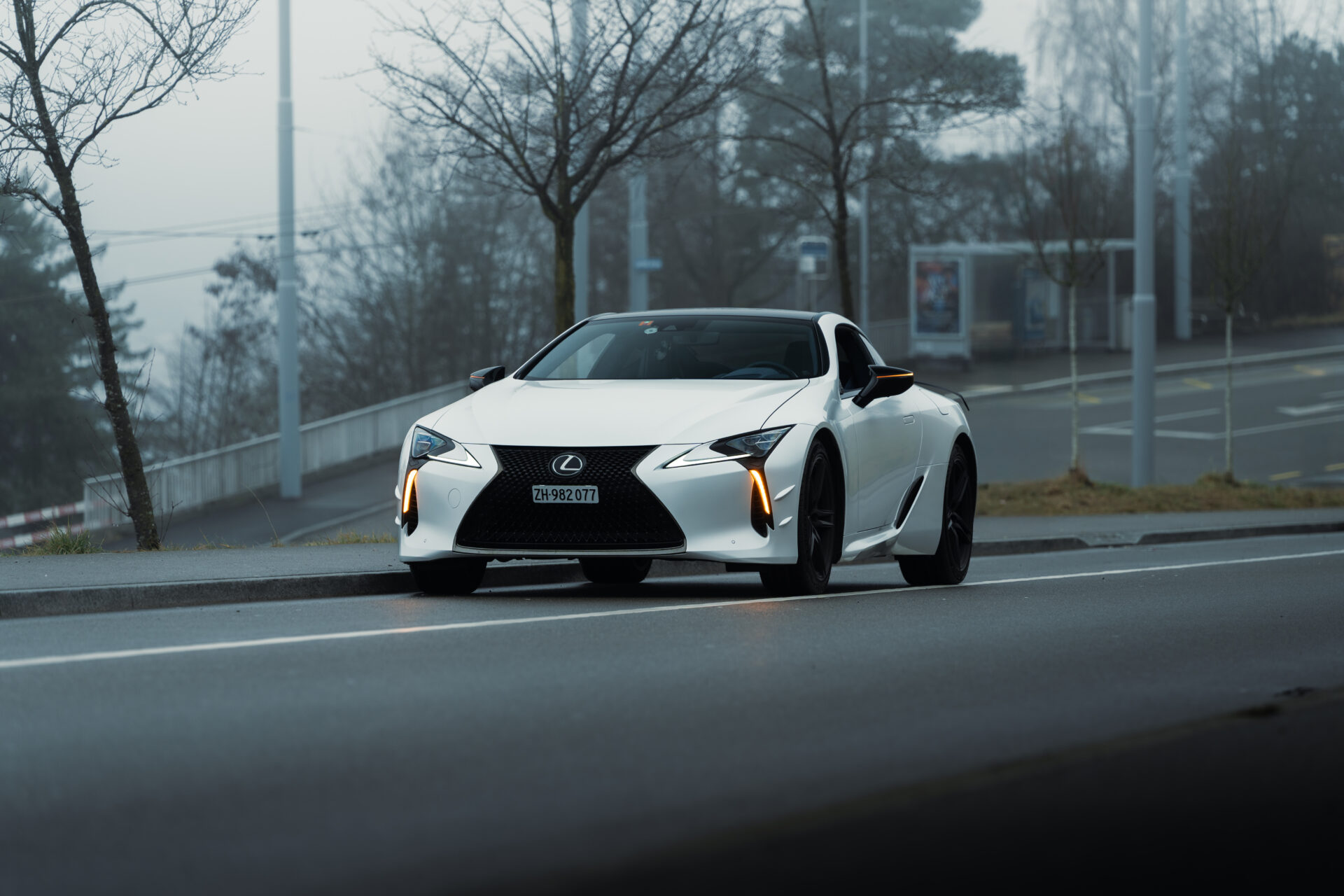 A Lexus LC500 Ultimate Edition parked by the road in foggy conditions with its hazard lights on