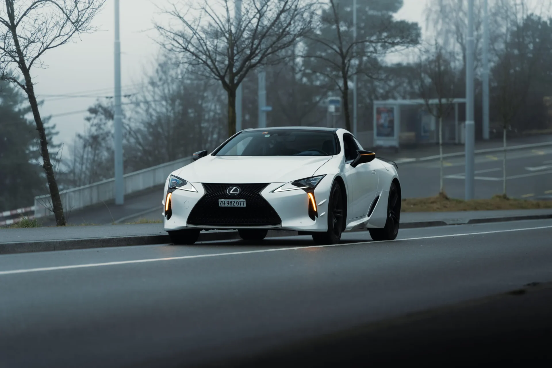 A Lexus LC500 Ultimate Edition parked by the road in foggy conditions with its hazard lights on