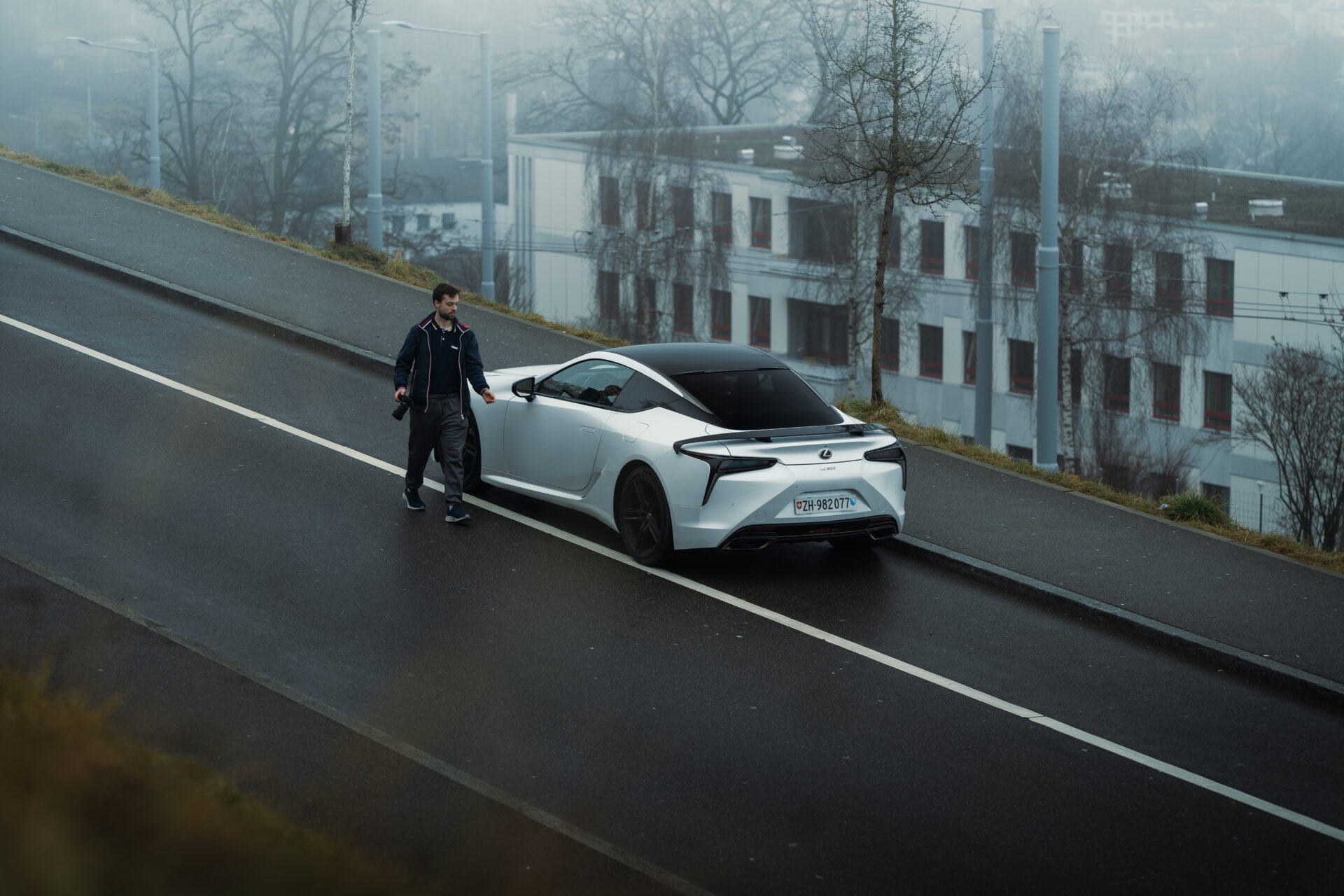 A foggy day in Zurich, Switzerland.A Lexus LC500 Ultimate Edition is parked and the owner is approaching it in the foreground of the scene